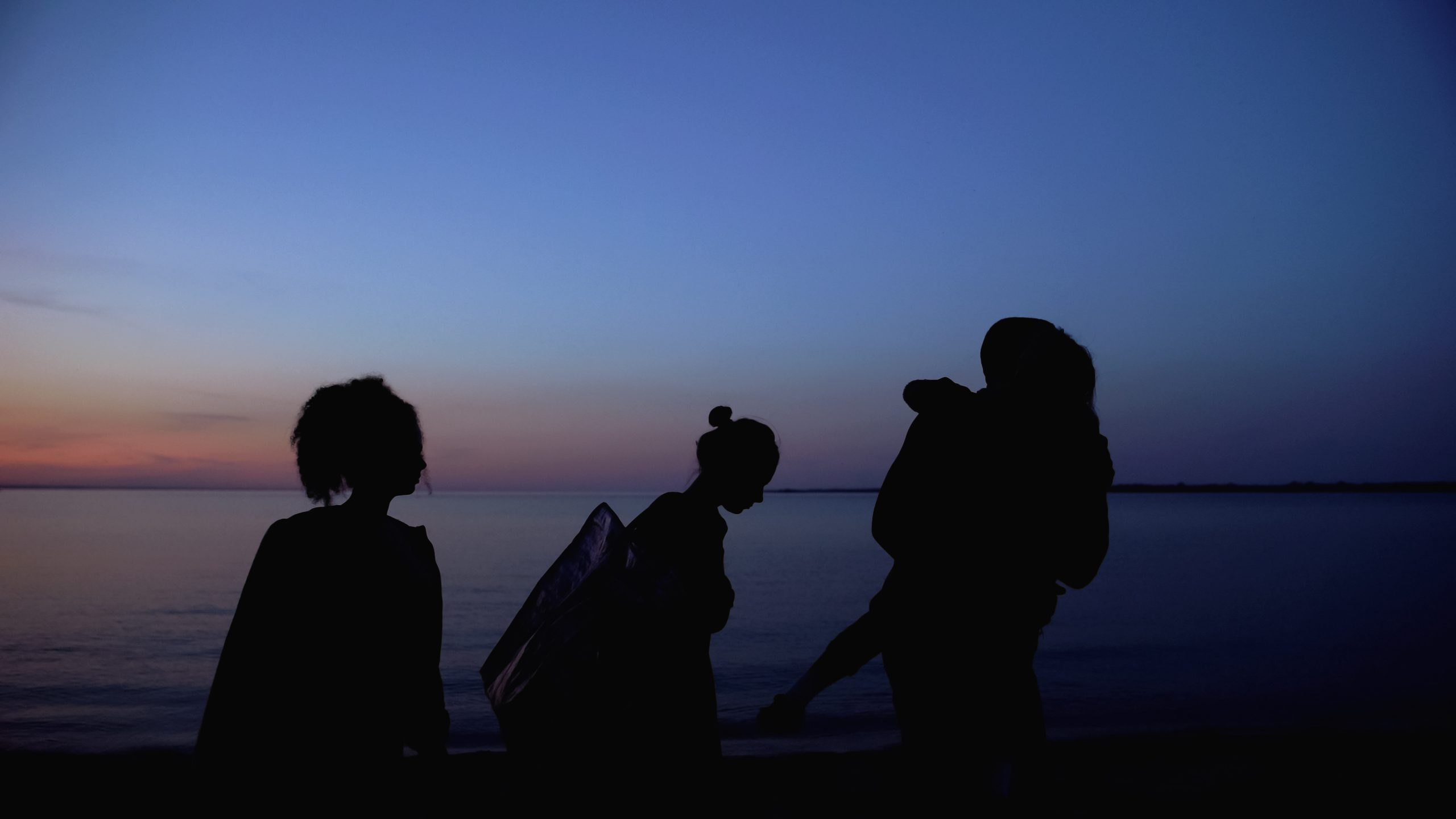 Refugee family with children walking at night with bags, illegal border crossing near a river.