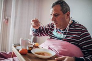 sick man uses eating soup in bed